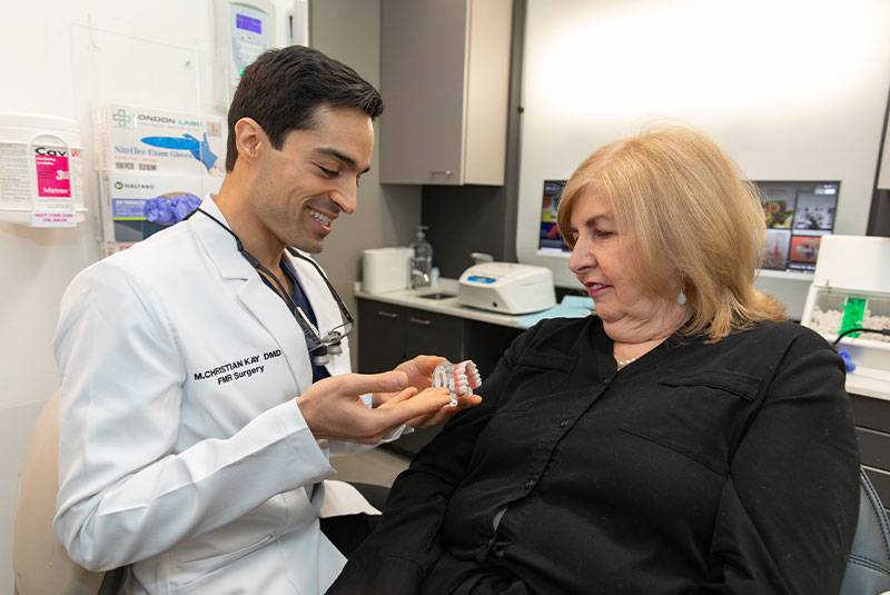 a dentist showing a denture to his patient